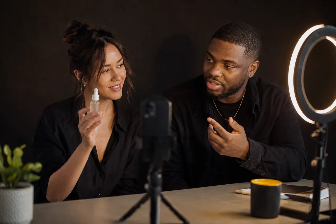 A content creator and a brand strategist collaborating in front of a phone mounted on a tripod with a ring light.