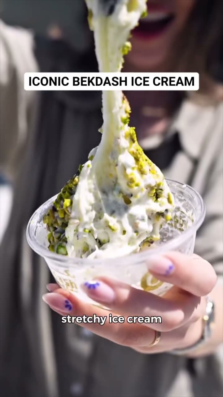 A hand holding a scoop of stretchy Arabian ice cream at Bekdash