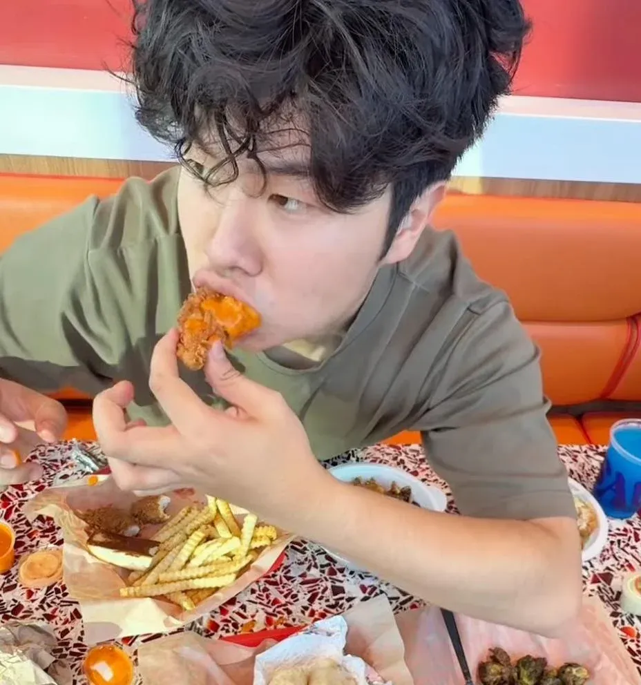 Bin Min Munch eating fried chicken at a red diner table